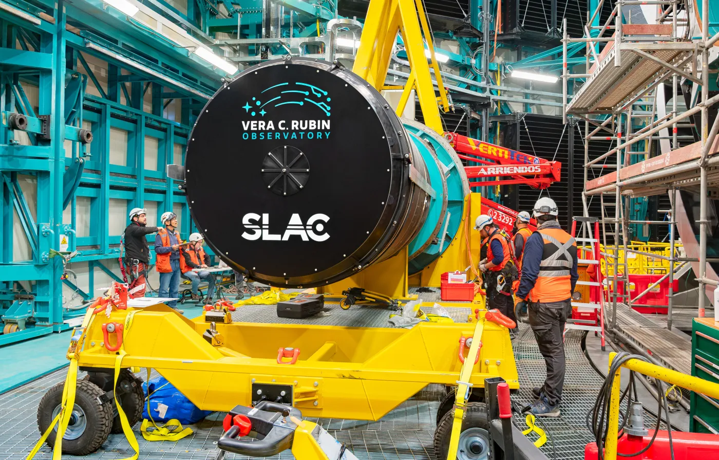 big circular closed lens at the center of the picture with workers surrounding it for installation.